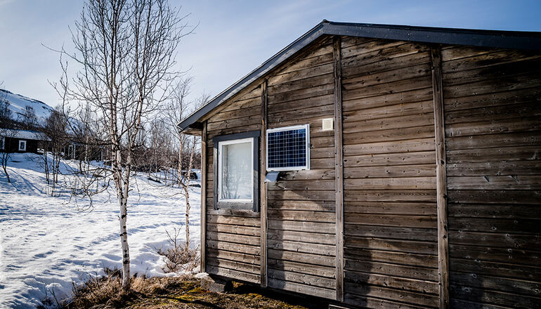 liten stuga i fjällmiljö  med solcellspanel